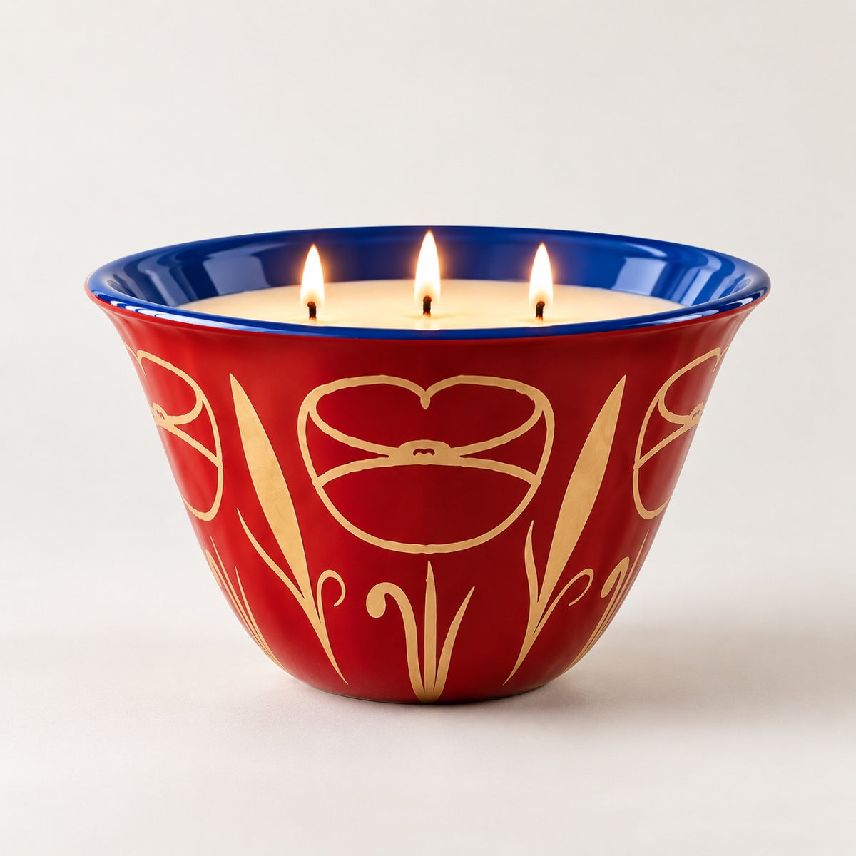 Coqlipot® 180 Festive Jewel Candle Edition, Rubis — ruby-red cement vessel, sapphire-blue rim, gold poppy motif, lit three-wick soy-blend wax candle